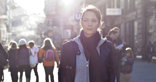 Does God Exist? - Photo of young woman walking in a crowded city street, looking deep in thought.